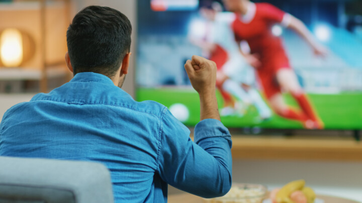 At Home Sports Fan Watches Important Soccer Match on TV, He Aggressively Clenches the Fist, Cheering for His Team.