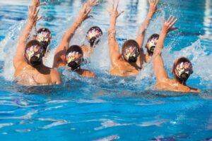 Synchronized swimming team performing a synchronized routine of elaborate moves in the water