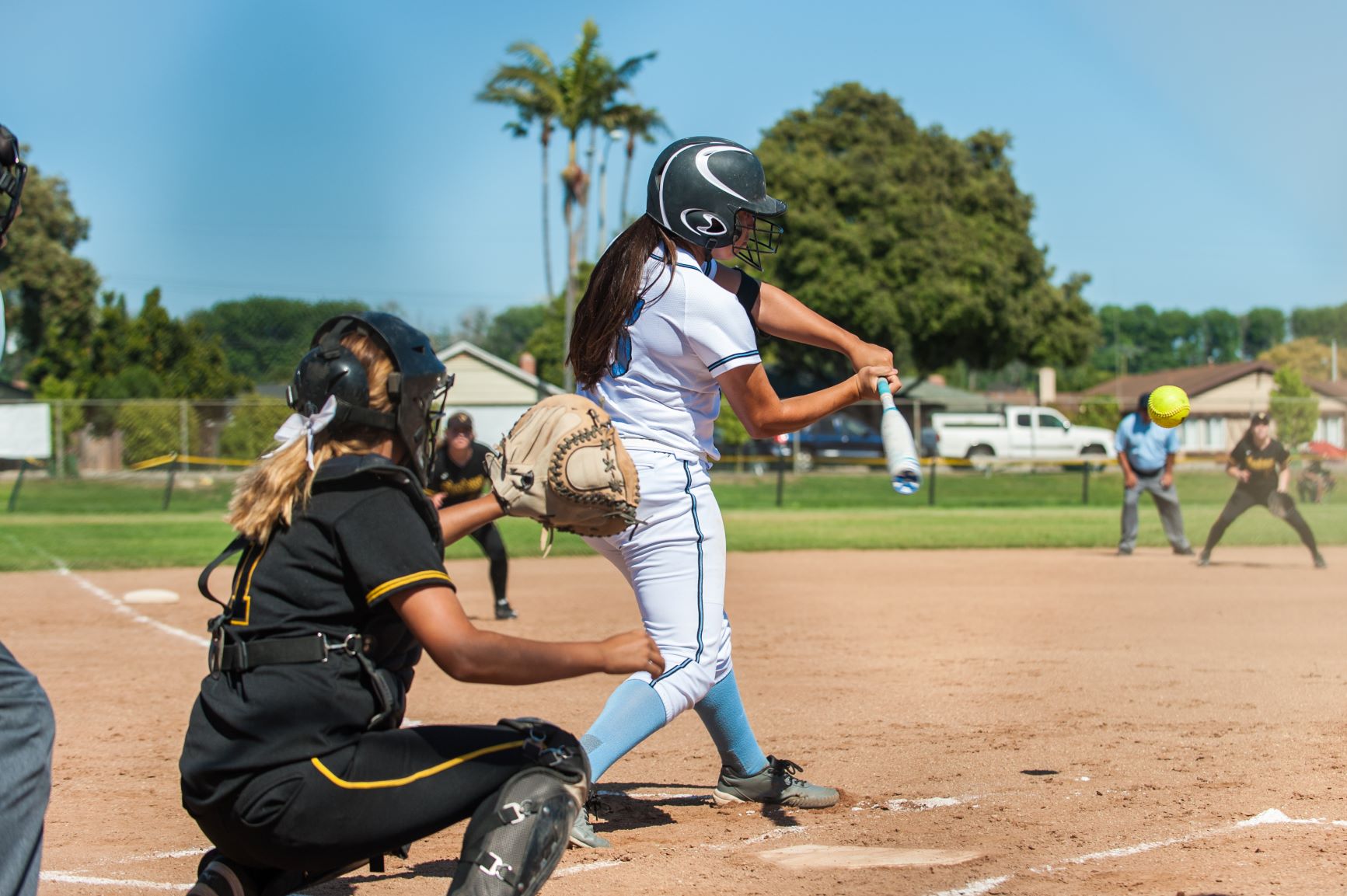 Catcher and hitter on first base during softball game.