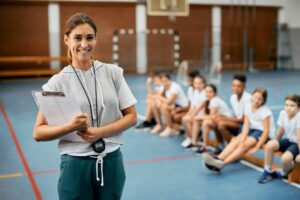 Portrait of happy physical education teacher during class at school gym.