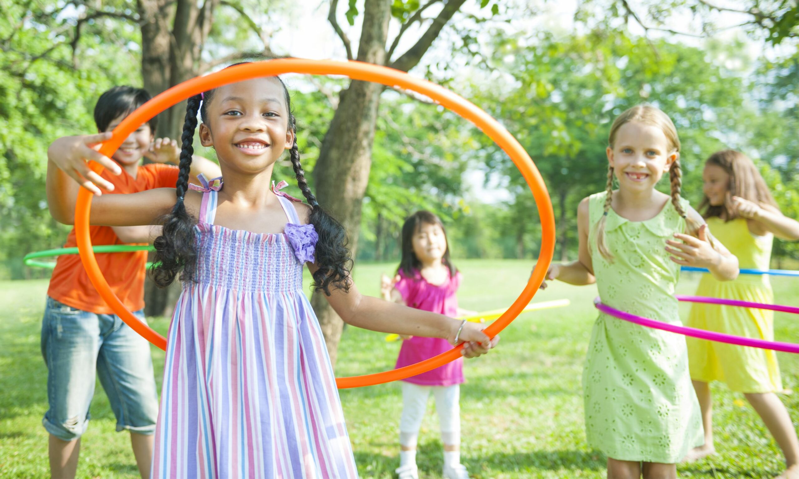 Des enfants d'origines diverses jouent avec des hula hoops