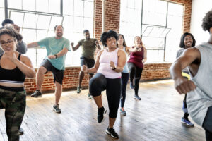 Group of people doing a fitness class together inside a room with a brick wall