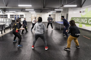 Des jeunes debout dans un cercle qui lancent une balle.