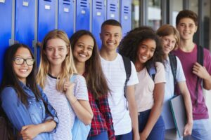 Group of diverse high school students standing in front of a row of lockers.