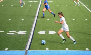 Teen female soccer player in Left wing position carrying the ball up the field