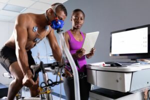 Man performing an exercise test on a stationary bike and wearing medical equipment.