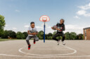 two kids jumping on the basketball court for a photo.