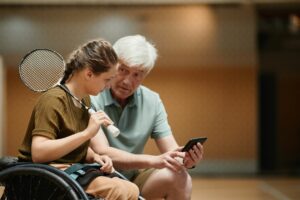 Coach reviewing video with wheelchair badminton athlete.