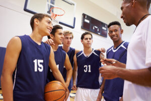 Male High School Basketball Team Having Team Talk With Coach