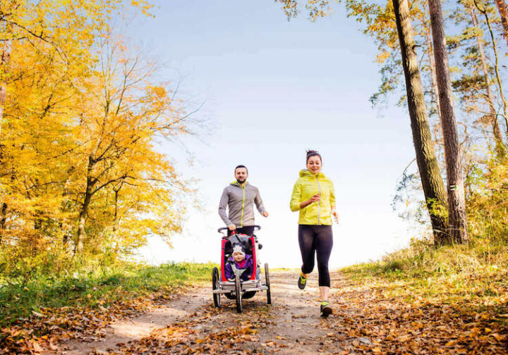 Parents jogging with child in stroller.
