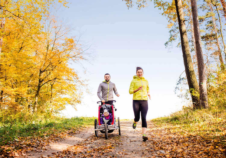 Parents jogging with child in stroller.