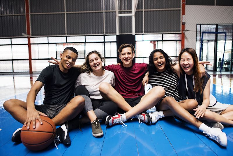Group of teenagers sitting on the floor of a gymnasium