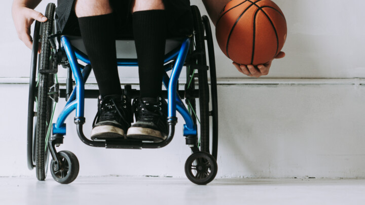 Athlete sitting in wheelchair holding a basketball in one hand