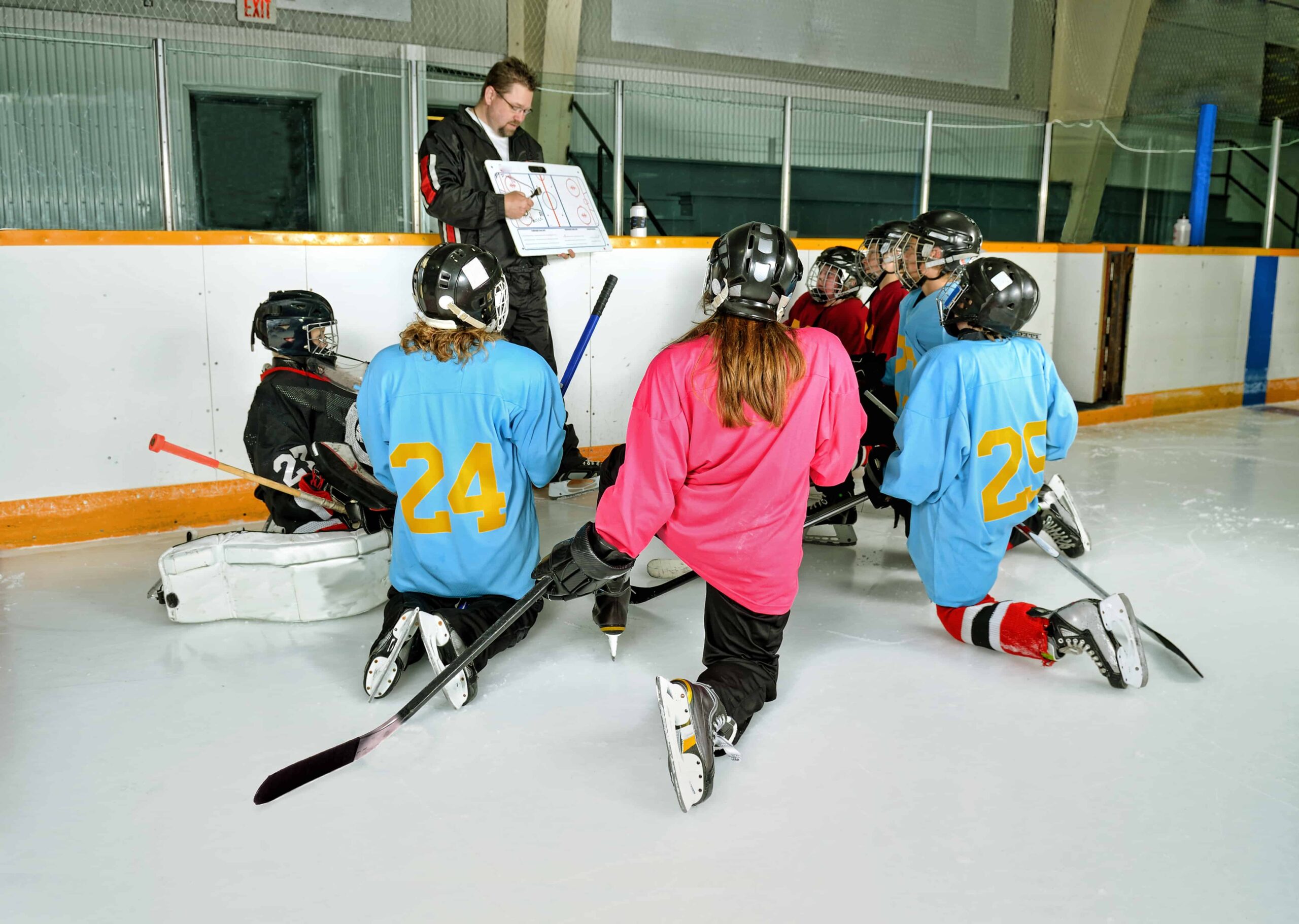 Hockey coach talking strategy with his girls hockey team