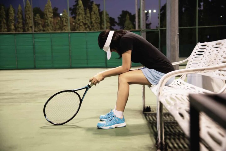 Sad lady tennis player sitting in the court after lose a match - people in sport tennis game 