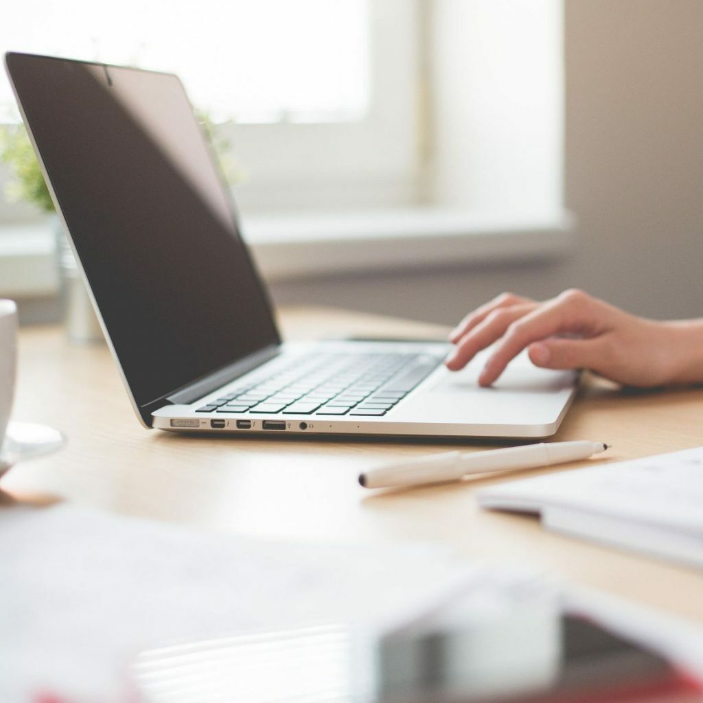 Laptop sitting on a desk with a hand typing