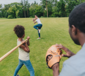 Family playing baseball in the park.