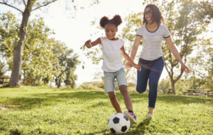 Mother and daughter playing soccer in the park.