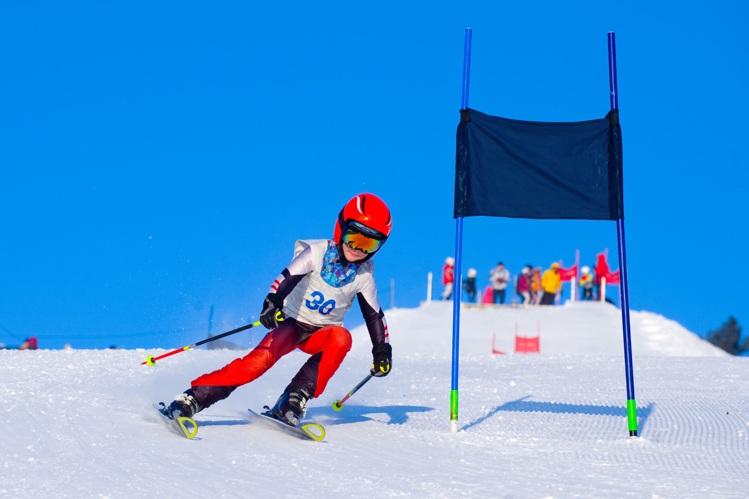 Young alpine skier descending a slope during a competition.