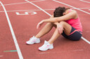 Female runner sitting on the track after training with her head in her arms
