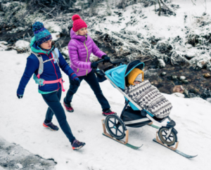 Femmes marchant sur un chemin recouvert de neige avec une poussette