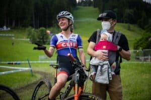 Catharine Pendrel on her road bike with her husband and baby daughter next to her.