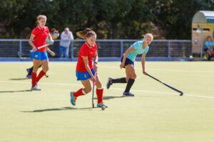 Field hockey female players run with ball in attack