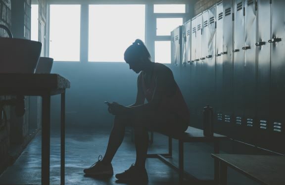 A female athlete in a locker room dealing with mental health