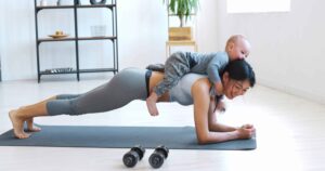 Mother with baby on her back as she does a core exercise