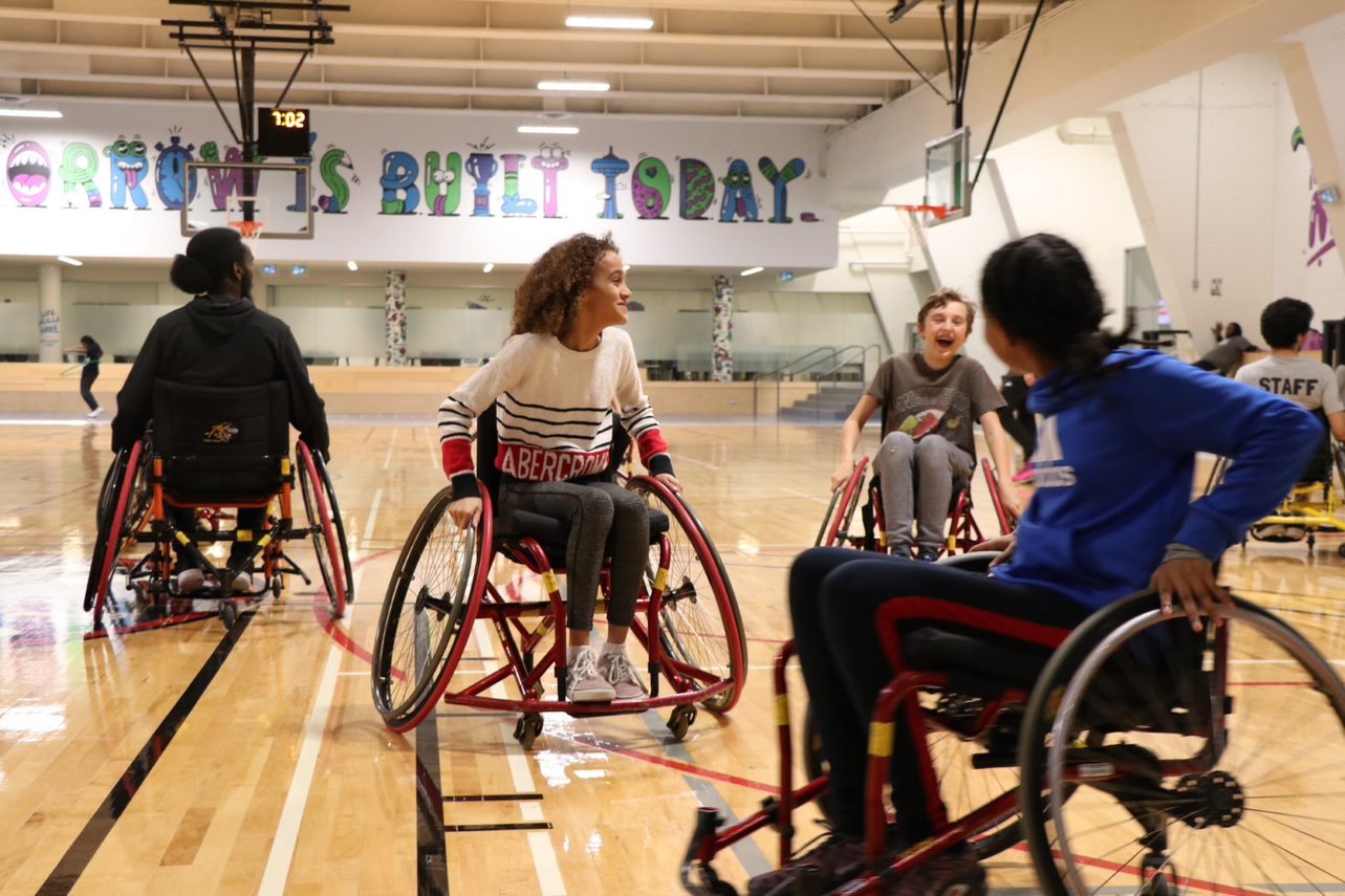 Youth participating in adapted sport using wheelchairs in a gymnasium