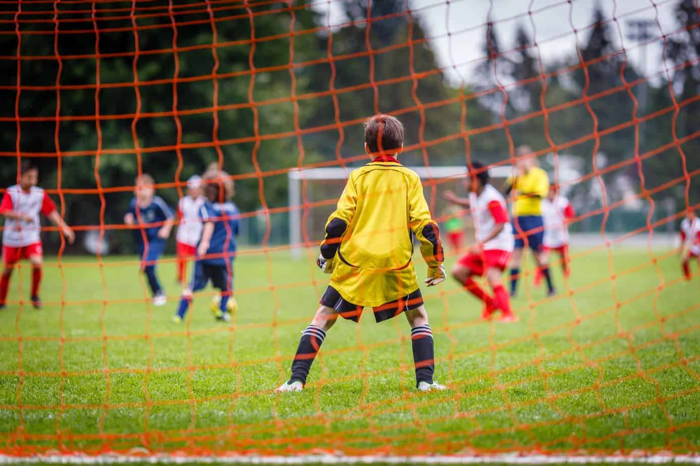 Young soccer goalie defending the net in the rain.