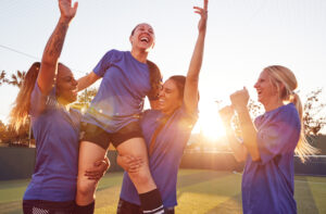 Womens Football Team Celebrating Winning Soccer Match Lifting Player up