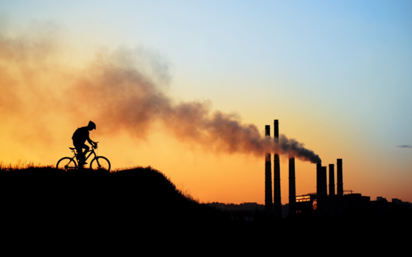 Un cycliste pédale à proximité de cheminées industrielles.