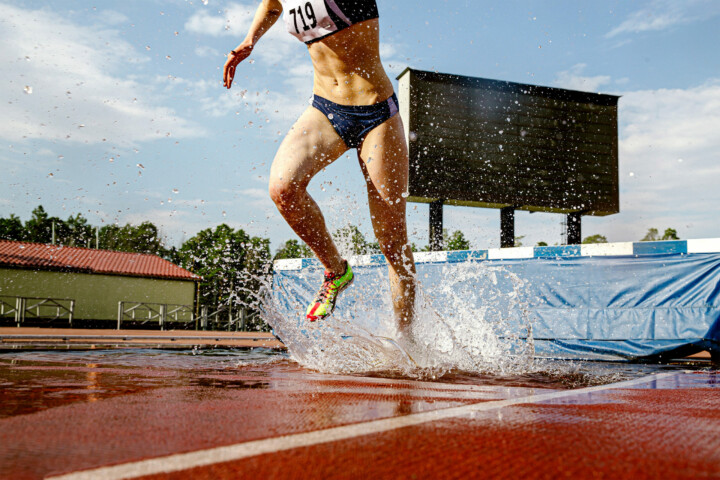 Female steeplechase athlete running through water