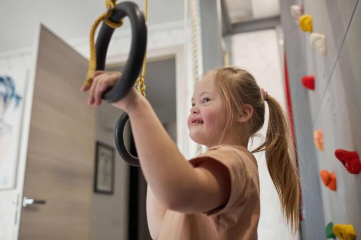 young girl with downs syndrome playing on gymnastic rings