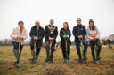 6 organizers of the Birmingham 2022 Commonwealth Games pose with shovels after planting trees.