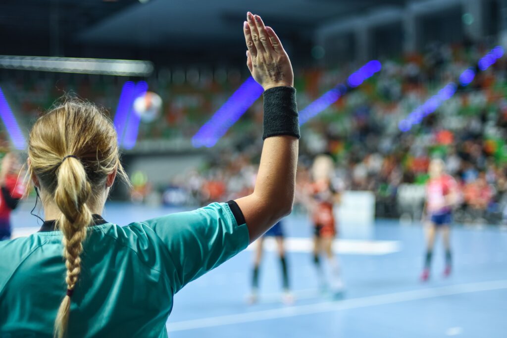 Female volleyball ref making a call with back to the camera