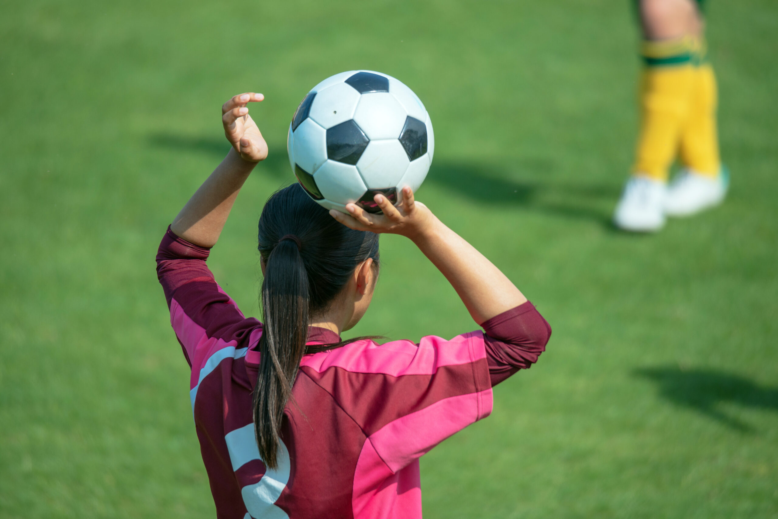 Young female soccer player throwing in a ball