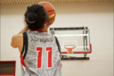 Girl shooting a basketball while wearing a jersey with Inuktitut on it