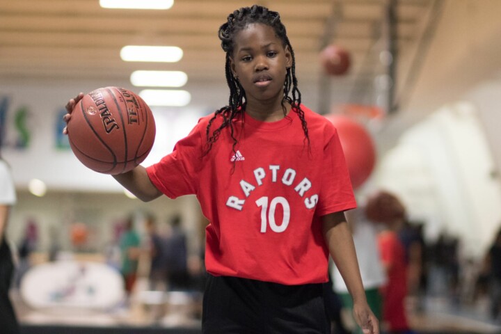 Girl dribbling basketball wearing a Raptors shirt