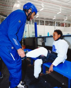 coach helps youth hockey player tie skates